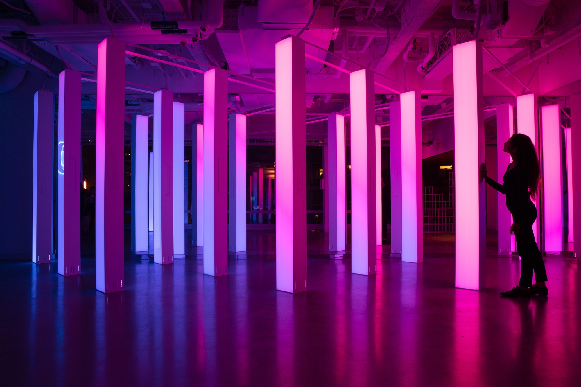 Wide angle of women standing next to columns with blue to pink gradient