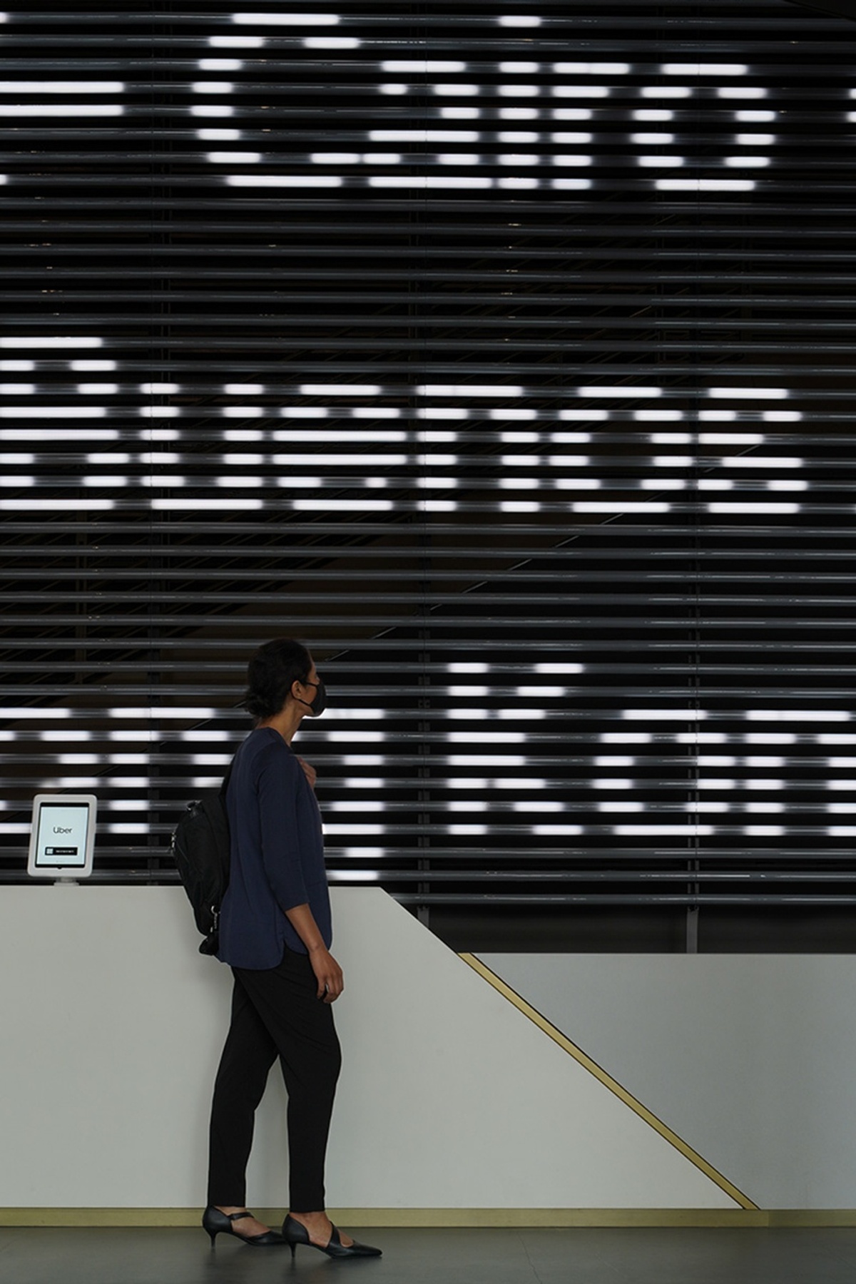 Woman standing at front desk with large typography of cities behind