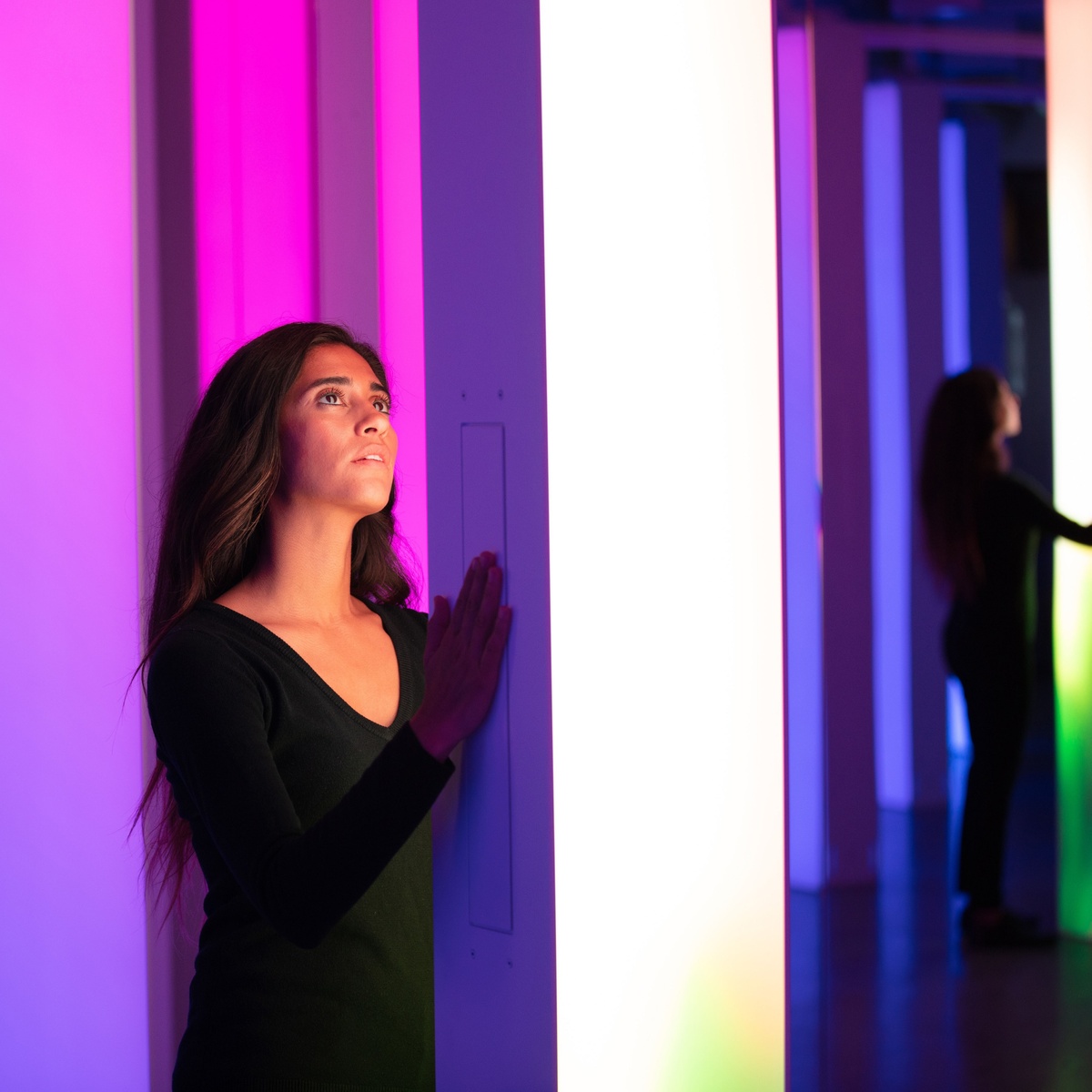 Young woman presses light column with white gradient