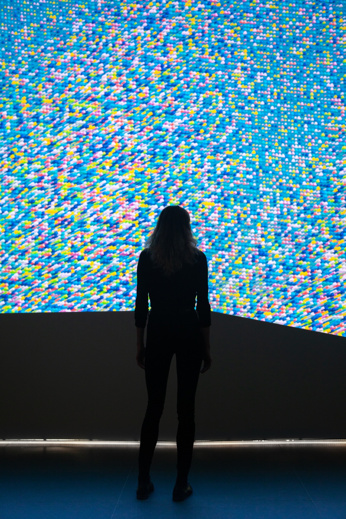 Woman silhouette against a large screen with data visualization graphics, in a blue dominant color palette