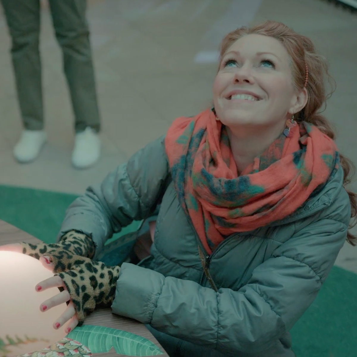 Young woman smiling and looking up as she places her hands on the orb