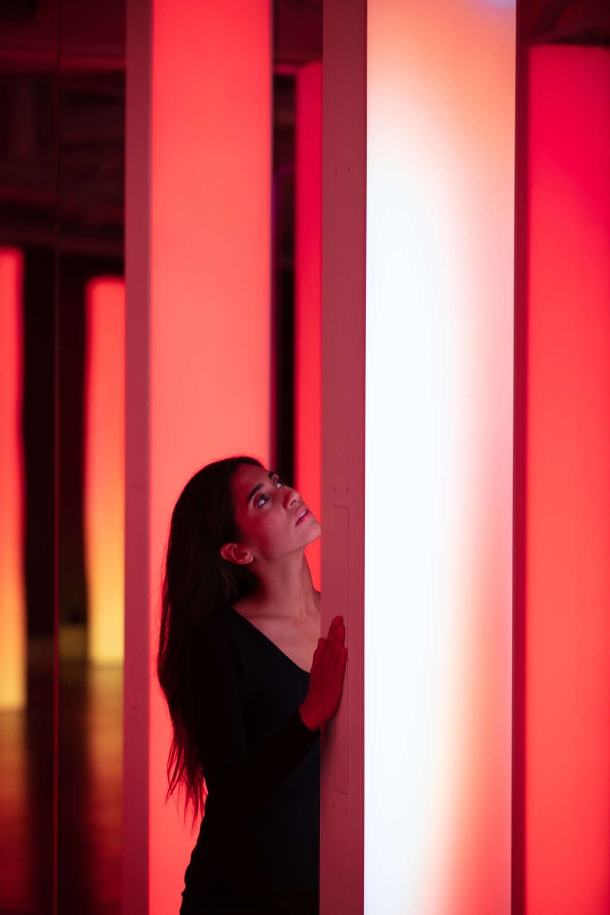 Young woman presses light column with peach gradient