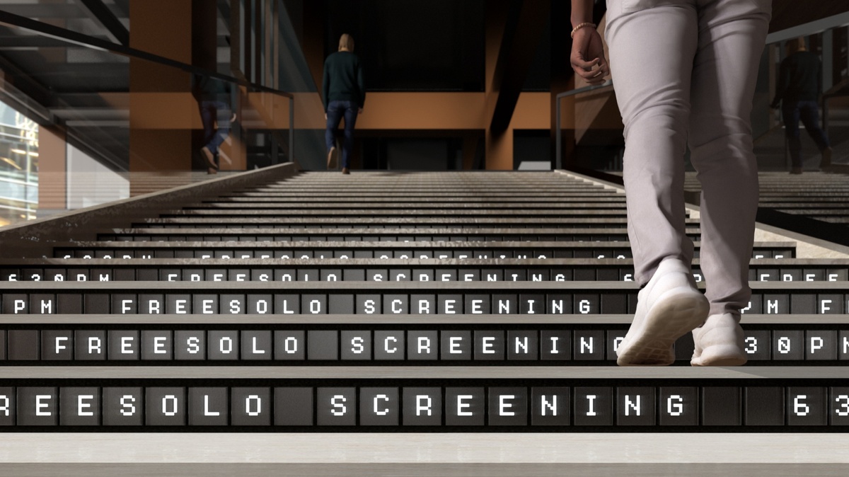 Low view of man walking up stairs with "Freesolo Screening" running across the risers