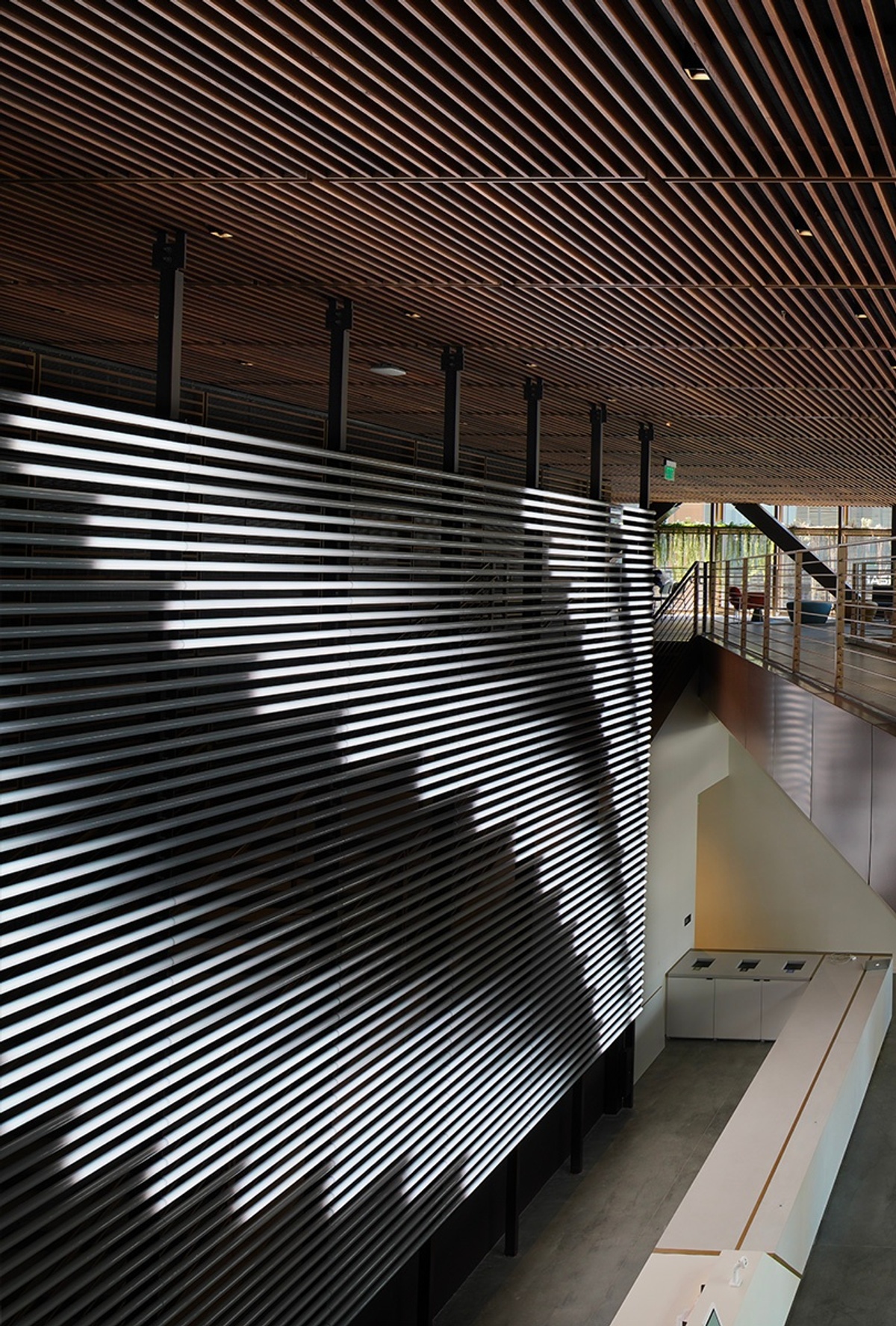 Overhead angle of light tubes behind front desk with black and white abstract content running horizontally