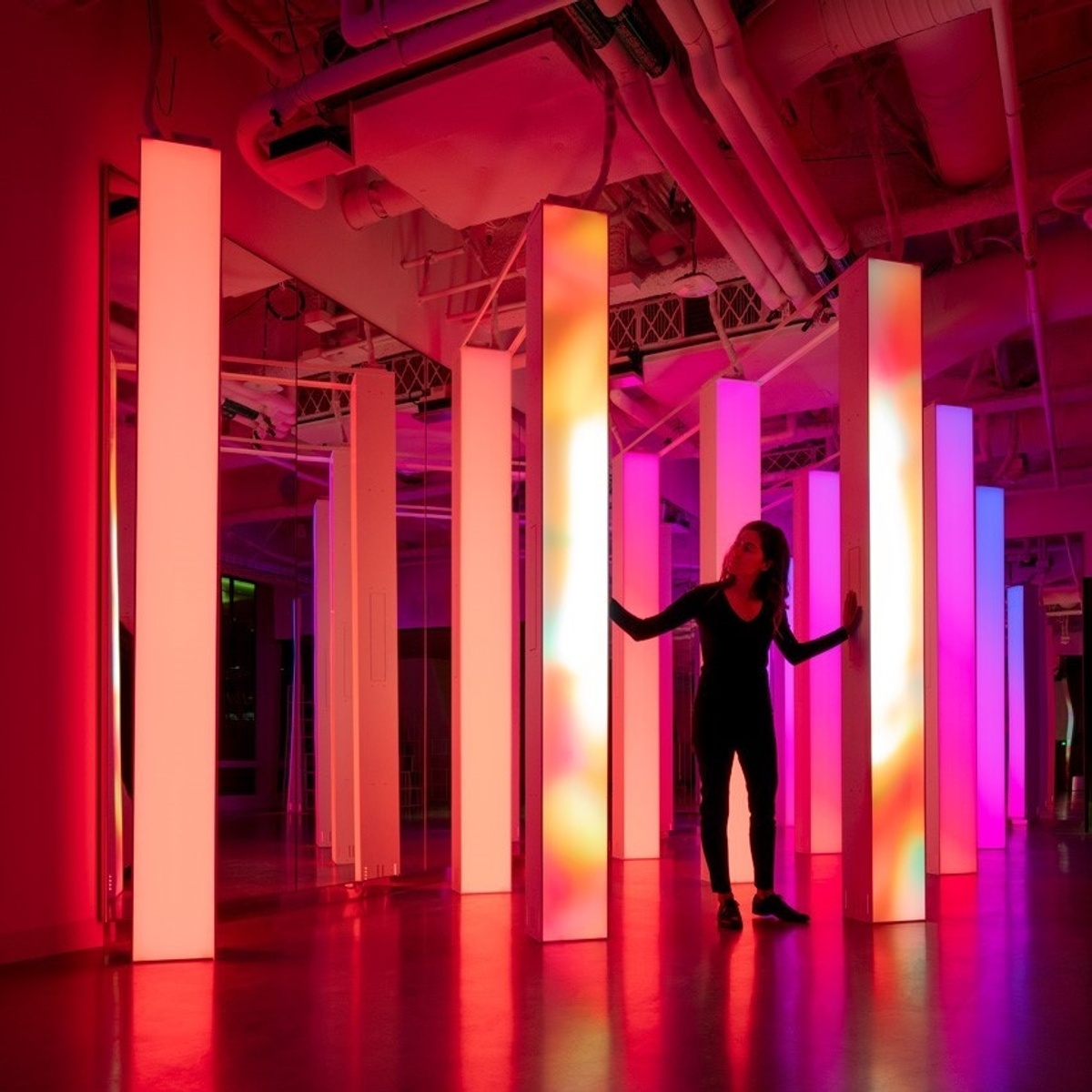 Young woman standing in between two columns with peach gradient