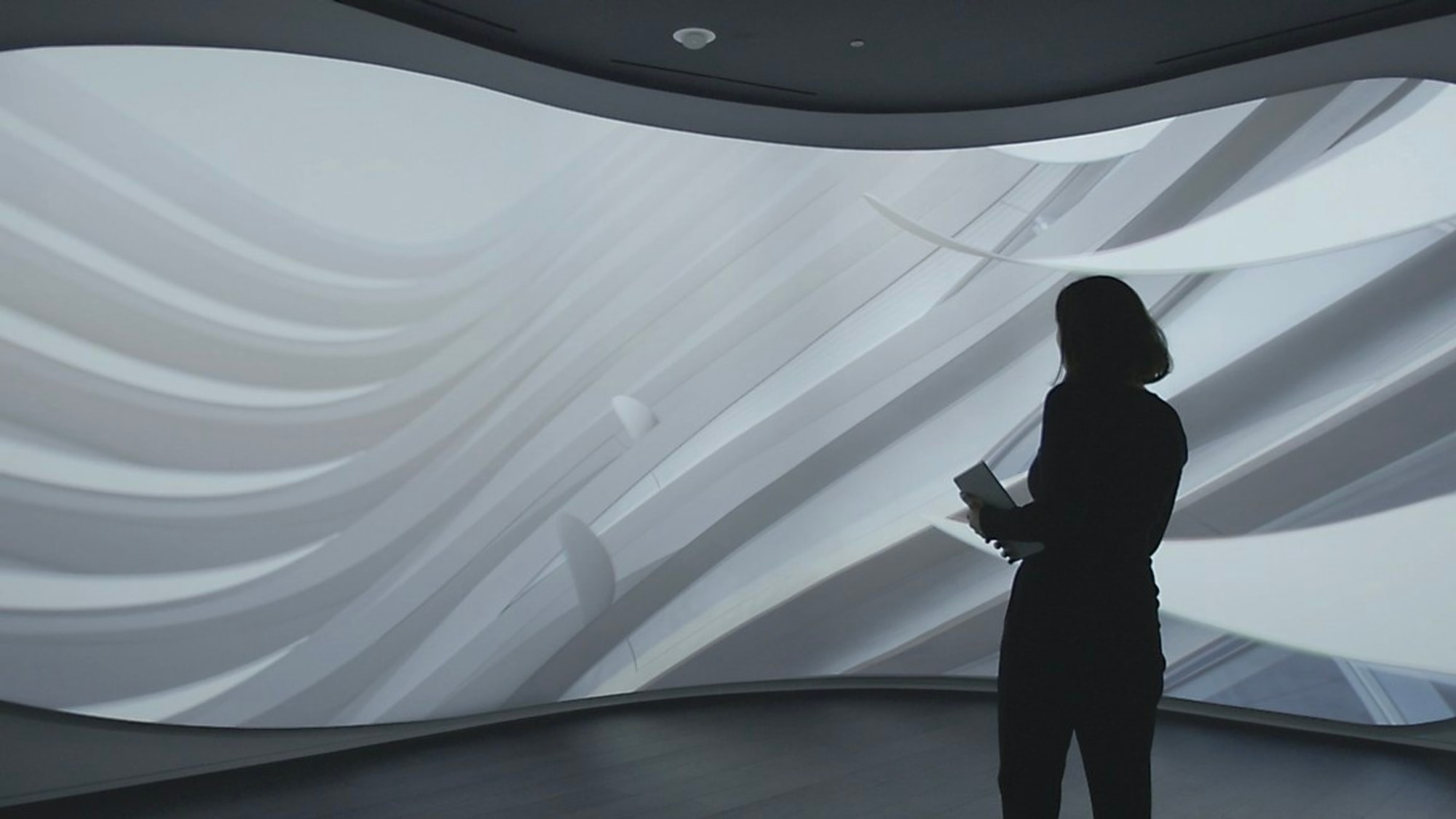 Woman standing at curved digital surface playing white abstract content