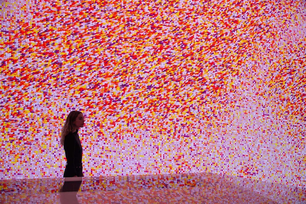 Side profile of woman in the experience, completely immersed by the graphic data visualisation, in a pink-dominant color palette