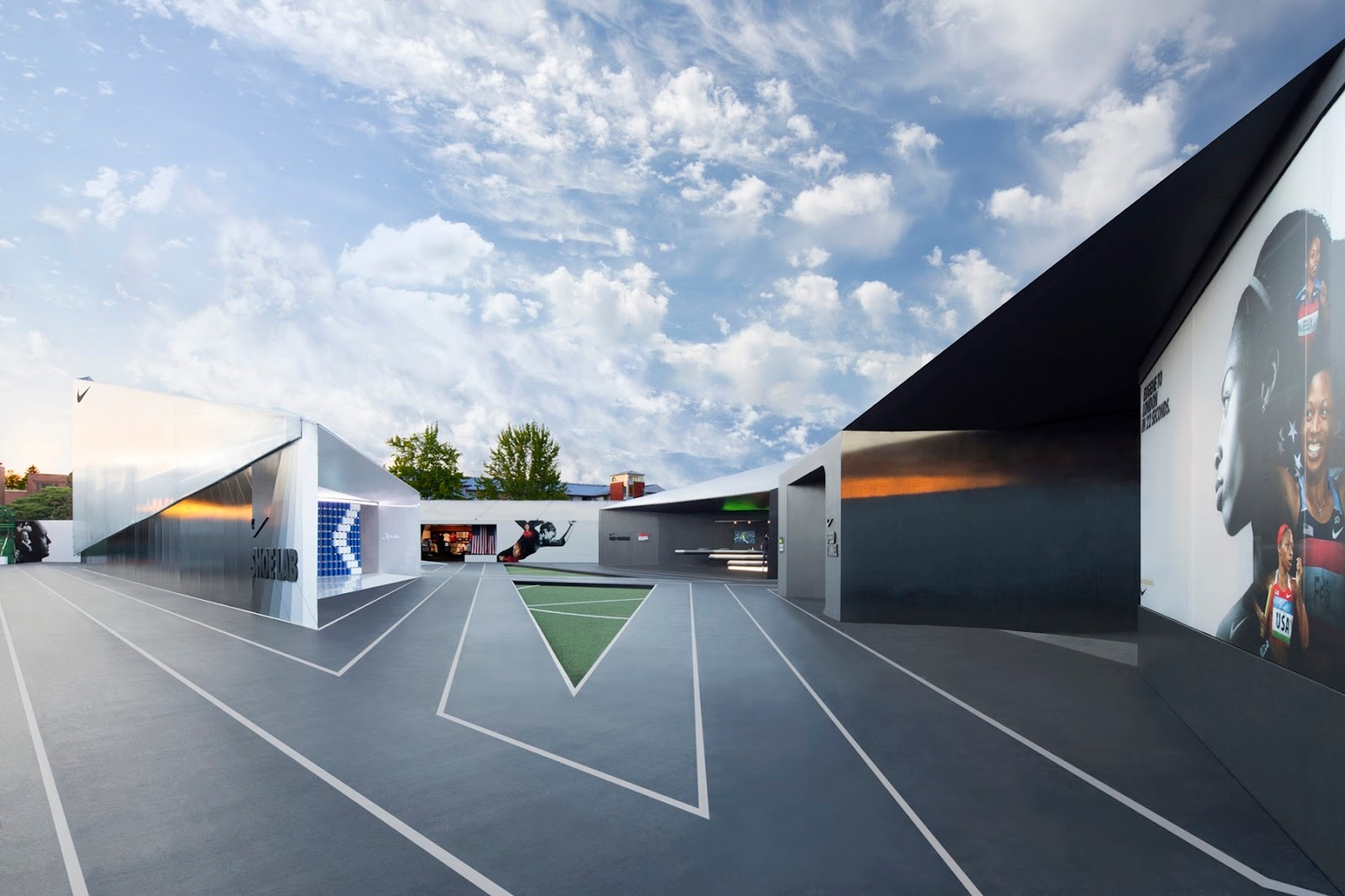 Photograph of track at Camp Victory, delineated by angular architectural structures, under a blue sky