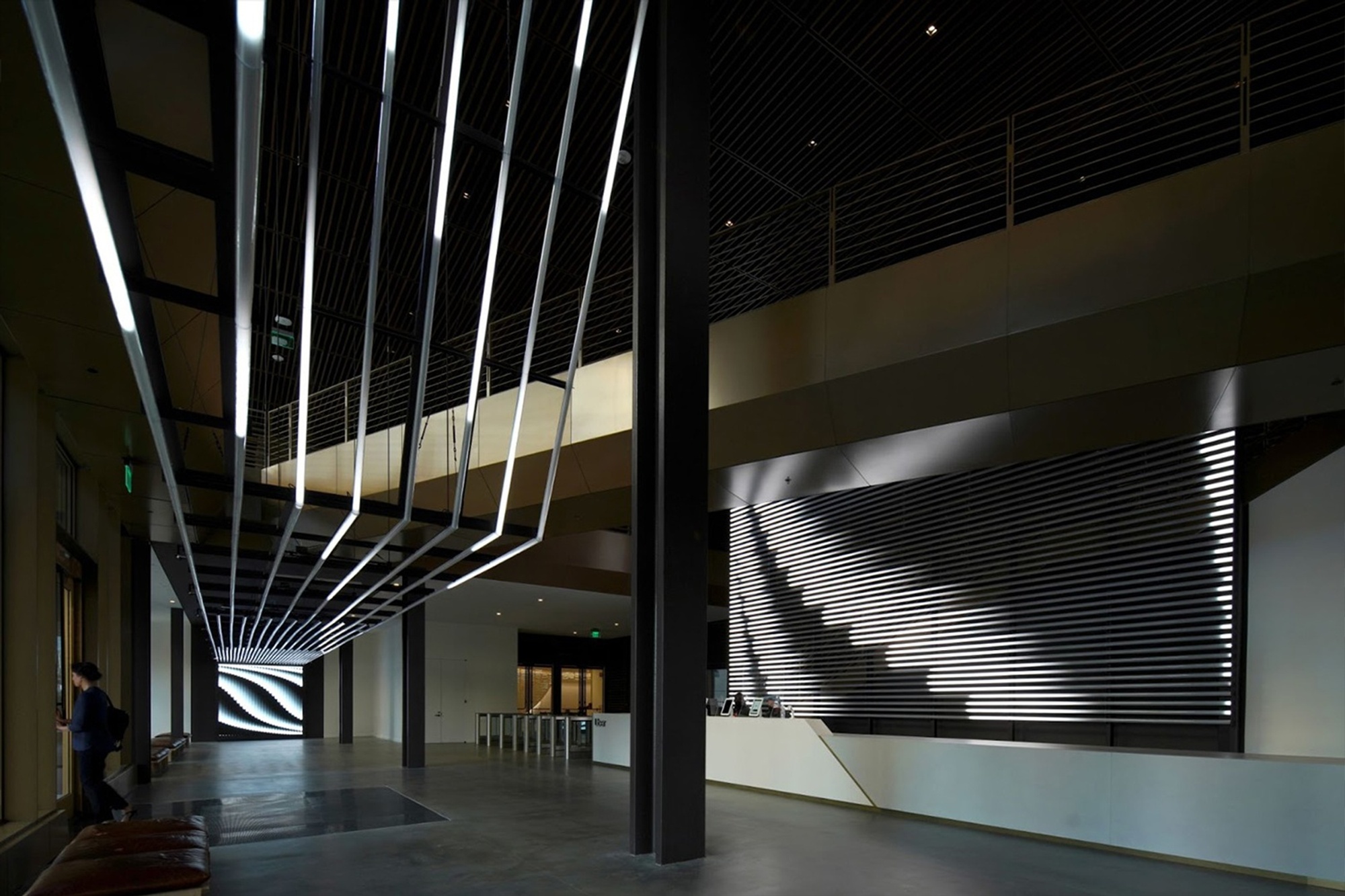 Wide angle of office with overhead light tubes and tubes behind front desk