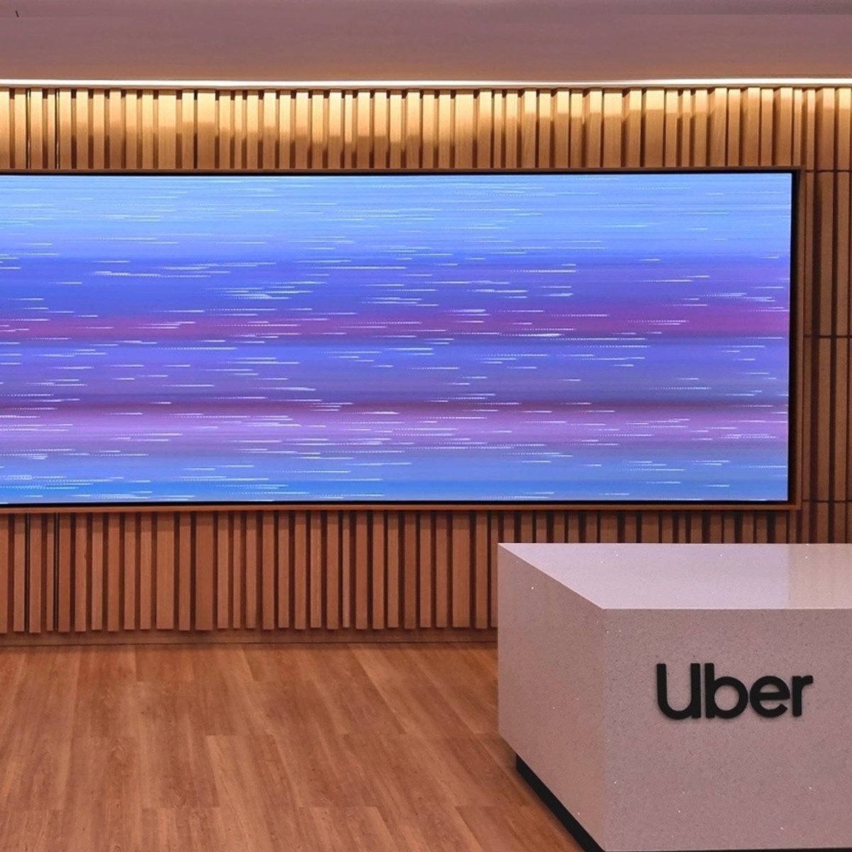 View behind front desk, with long rectangular high-resolution blue-purple content on wooden wall