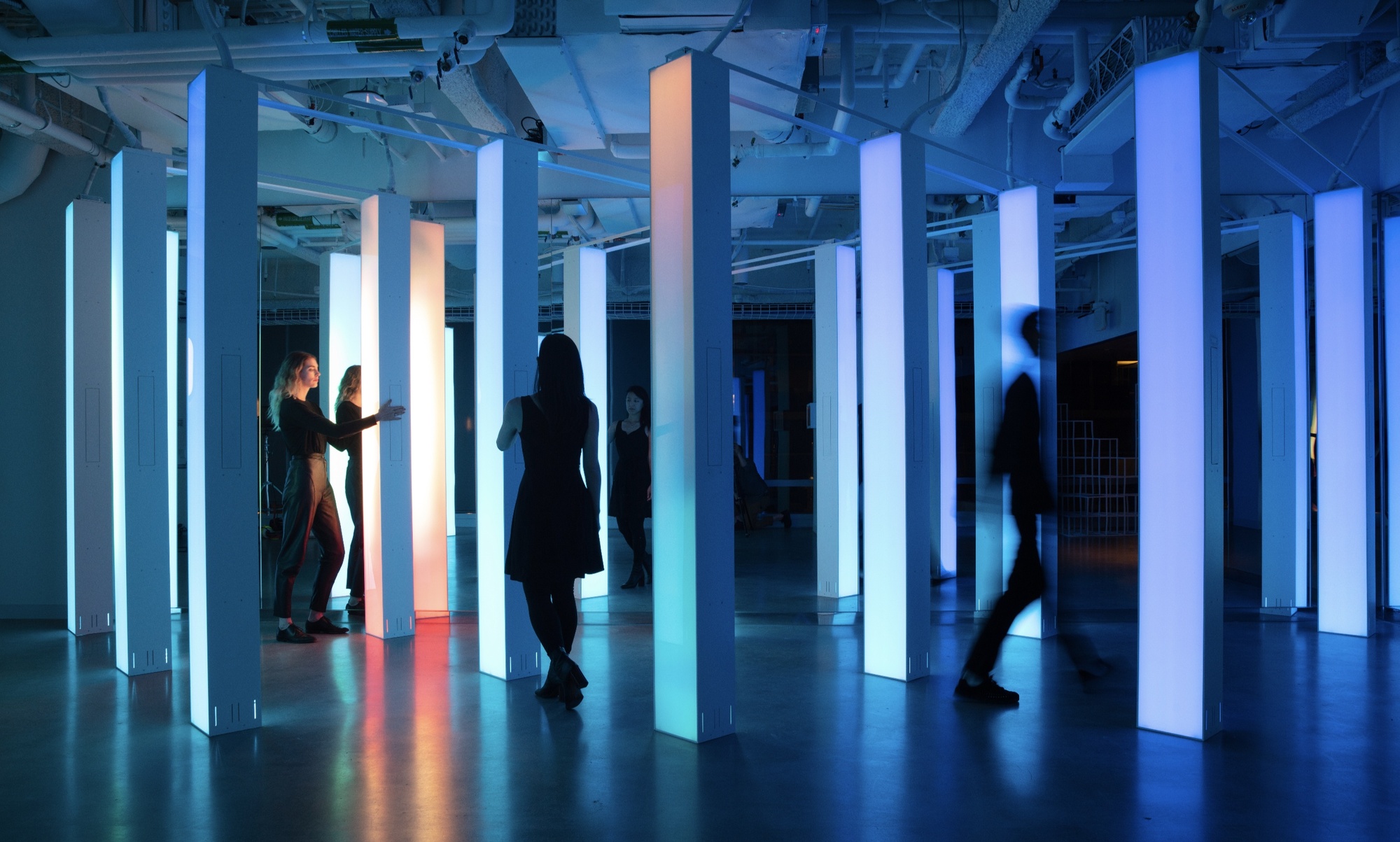 Group of people walking in between pillars with orange to blue gradient