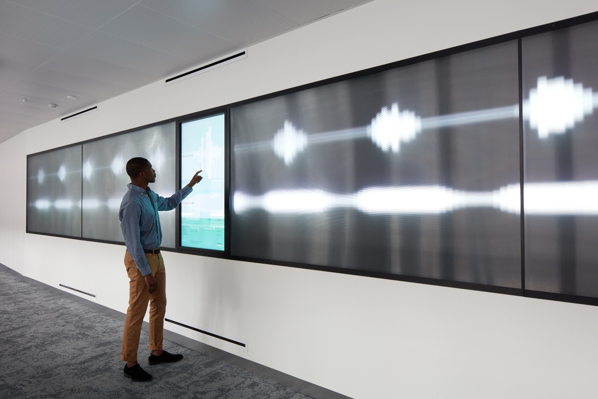 Photograph of man touching screen with pulsing white lines radiating from sides of screen