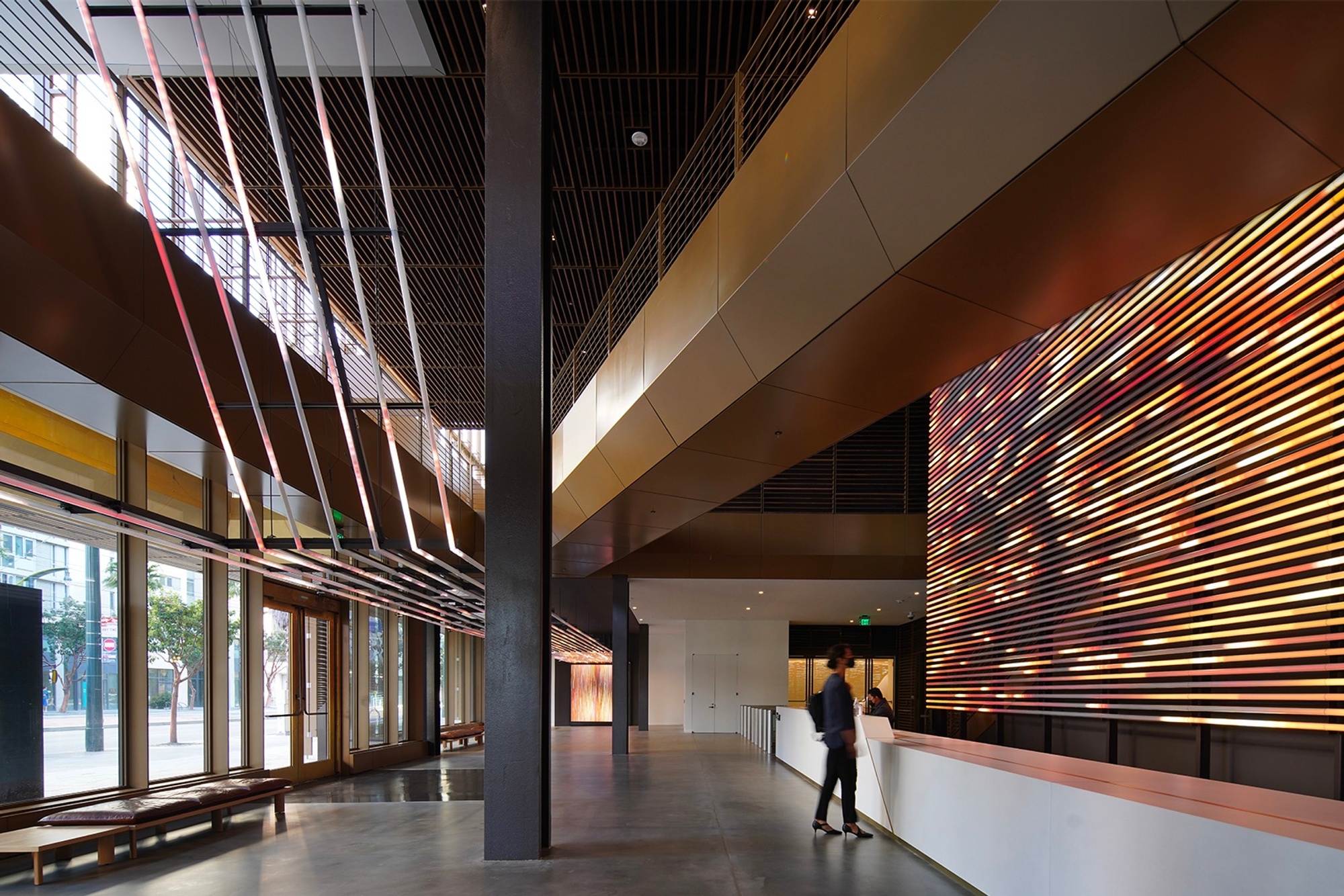 Angle view towards front desk with red-orange abstract content playing on light tubes behind desk and on overhead structure